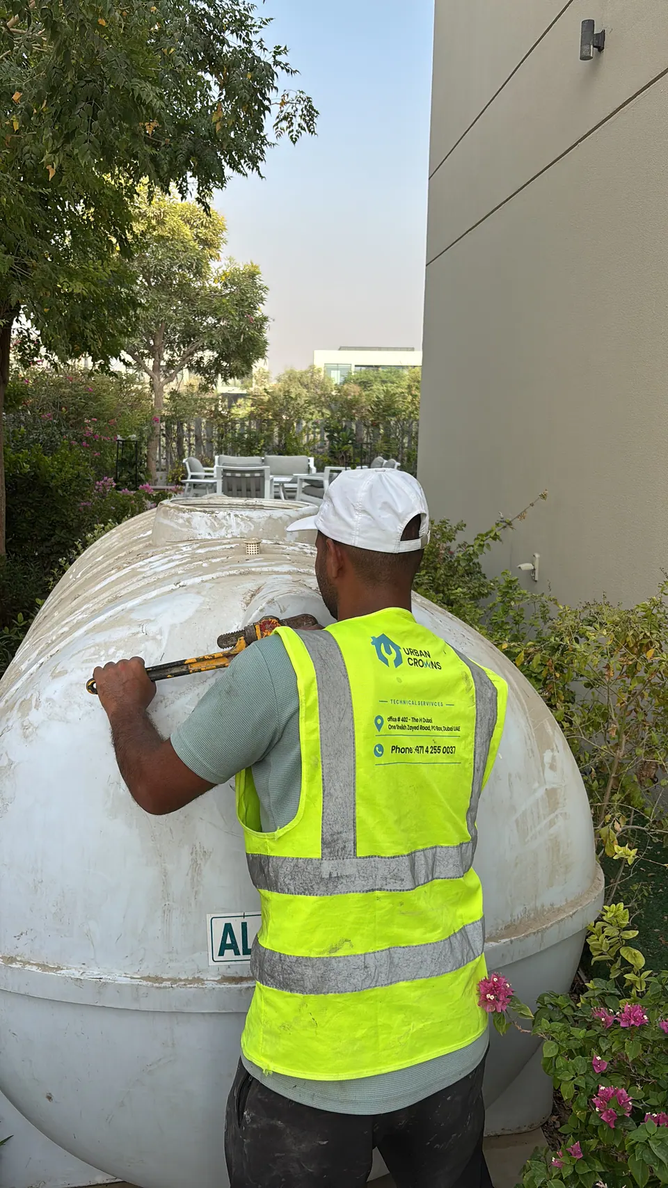Urban Crown technician in hi-vis cleaning and sanitising a rooftop water tank