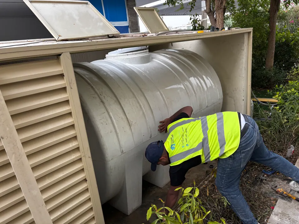 Technician servicing the outside of a water tank on a villa plot