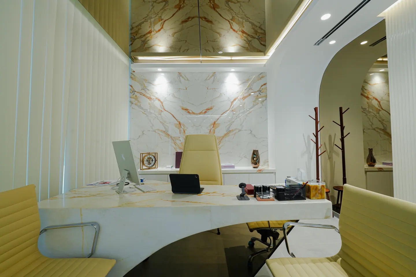 Curved reception desk in book-matched marble with a concealed-lit timber ceiling — Kings Woods Real Estate office fit-out by Urban Crown, Dubai