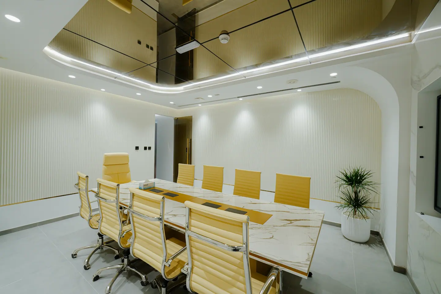 Boardroom with a marble conference table beneath a curved gold-toned ceiling feature with continuous linear lighting — Kings Woods Real Estate office fit-out by Urban Crown, Dubai